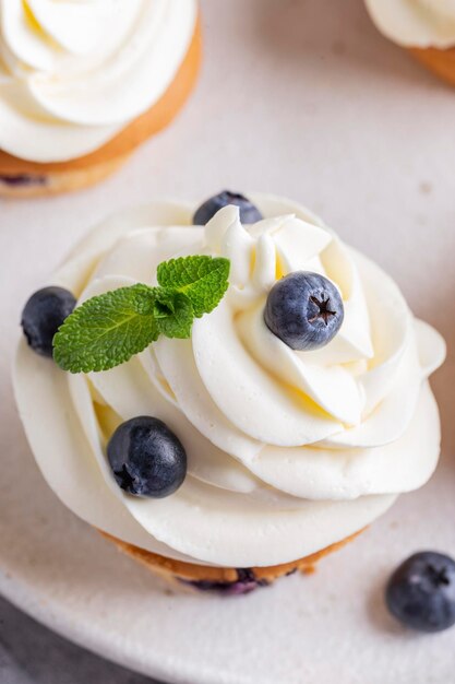 Cupcakes de arándanos decorados con crema de vainilla