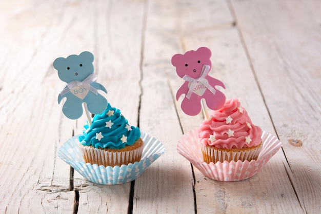 Cupcakes azuis e rosa para chá de bebê na mesa de madeira