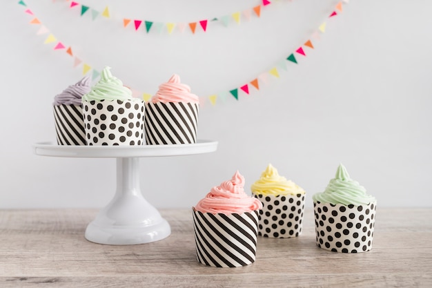 Foto cupcakes buttercream color pastel delante de banderines