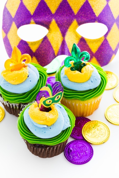 Cupcakes chiques decorados com folha e máscara para festa de Mardi Gras.