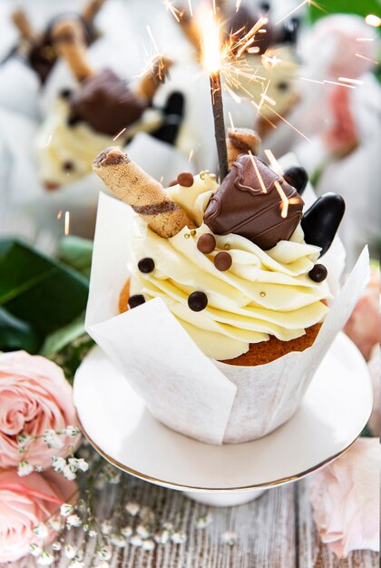 Cupcakes de chocolate con bengalas encendidas sobre la superficie de madera blanca