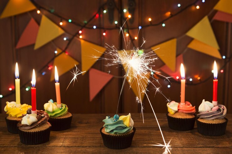Foto cupcakes de chocolate con glaseado de colores y velas sobre fondo festivo con guirnalda. maqueta de tarjeta, espacio de copia. cumpleaños, fiesta, concepto de vacaciones