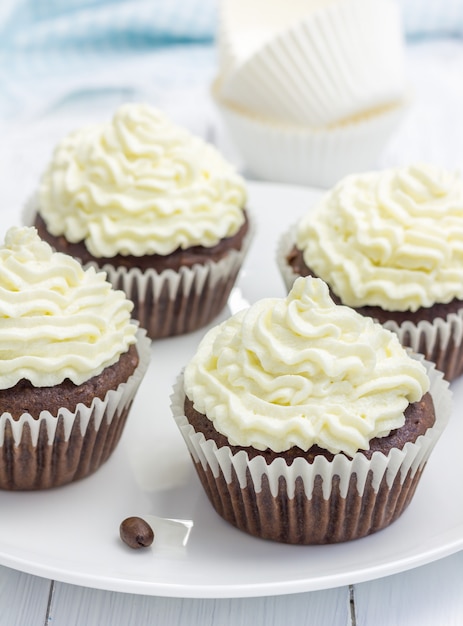 Cupcakes de chocolate con glaseado de queso ricotta en la placa blanca.