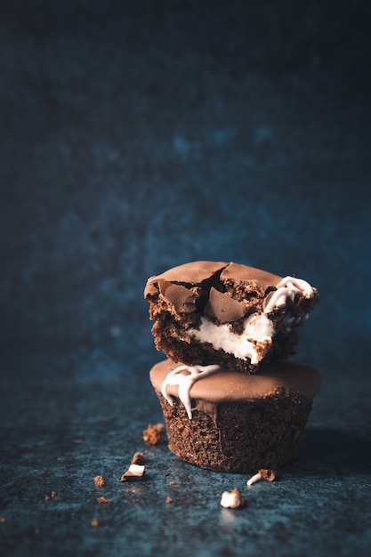 Cupcakes de chocolate rellenos de crema sobre un fondo azul oscuro Vertical