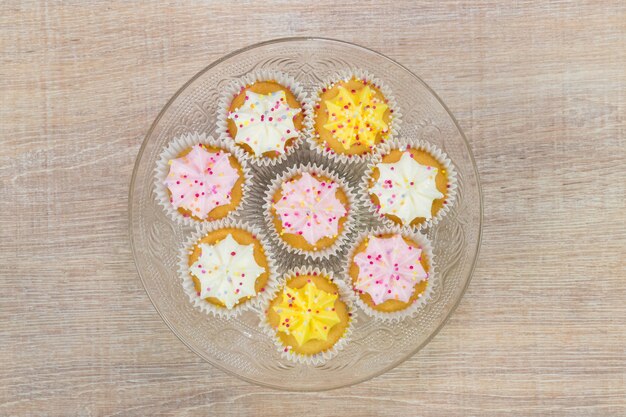 Cupcakes coloridos sobre un fondo de madera blanca. Vista superior con espacio para el texto.