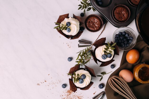 Cupcakes com creme e mirtilos na mesa da cozinha