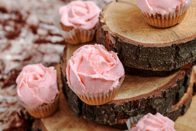 Cupcakes com creme rosa sobre fundo de madeira.