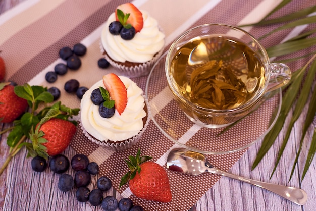 Cupcakes com morangos e mirtilos. Cupcakes com uma xícara de chá.