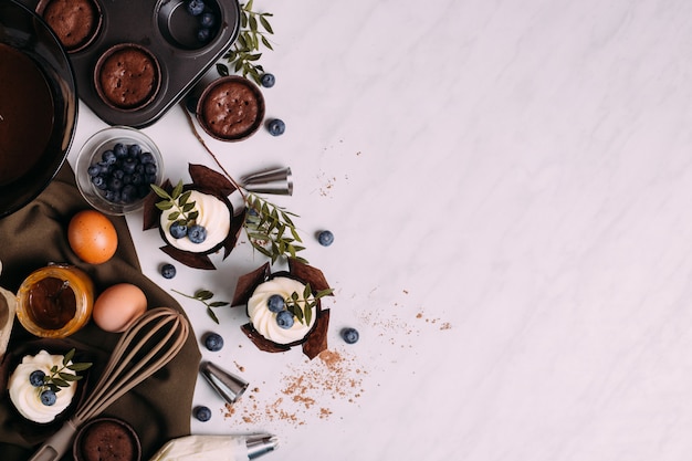 Cupcakes con crema y arándanos en la mesa de la cocina