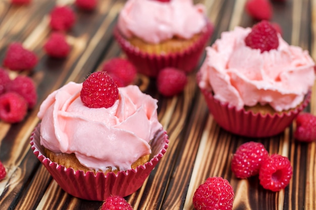 Cupcakes con crema rosa y frambuesas frescas.