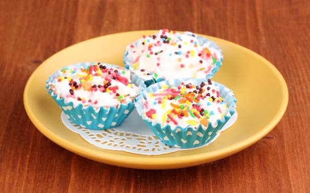 Cupcakes cremosos en plato sobre fondo de madera