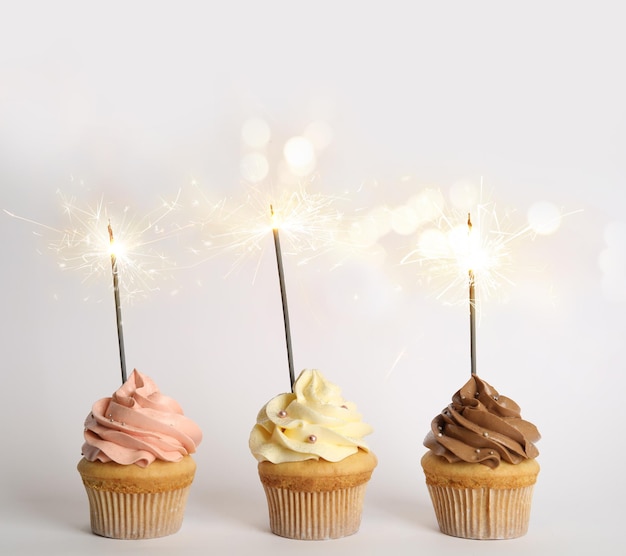 Cupcakes de cumpleaños con bengalas sobre fondo blanco.