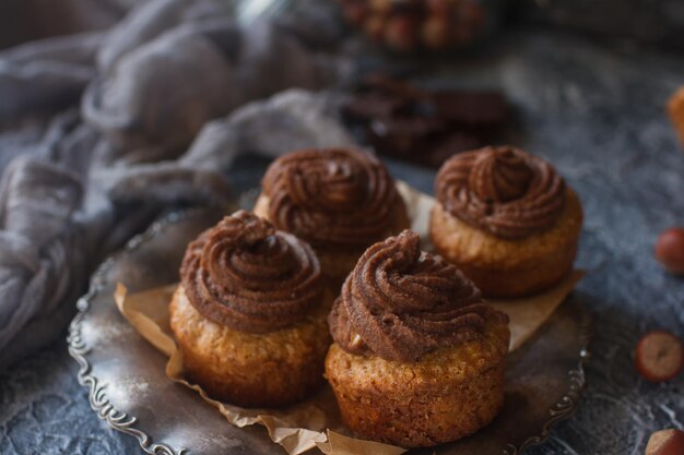 Cupcakes de baunilha caseiros com cobertura de chocolate na mesa de pedra escura