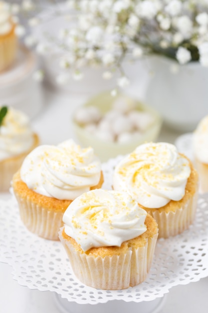 Cupcakes de baunilha com cobertura de creme de queijo em um carrinho de bolo branco