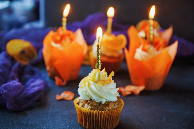 Cupcakes de cenoura de páscoa com creme de baunilha e laranjas de caramelo em fundo escuro de pedra