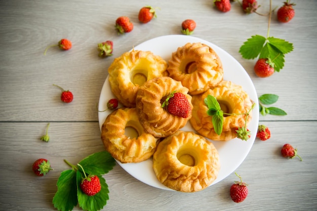 Cupcakes de coalhada doce cozida com morangos frescos e hortelã em uma mesa de madeira