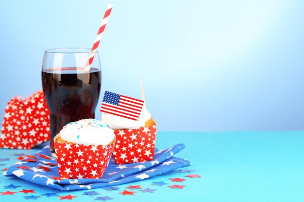 Cupcakes de férias patrióticas americanas e copo de coca-cola em fundo azul