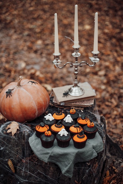 Cupcakes de Halloween e decoração de férias em folhas de bordo entre árvores na temporada de outono ao ar livre