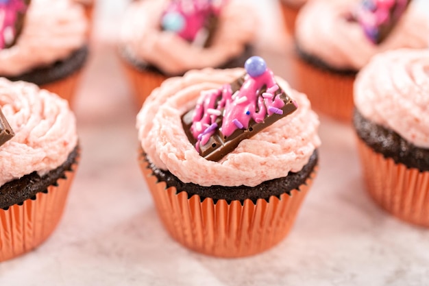 Cupcakes de morango com chocolate recém-assados, guarnecidos com mini chocolates rosa gourmet