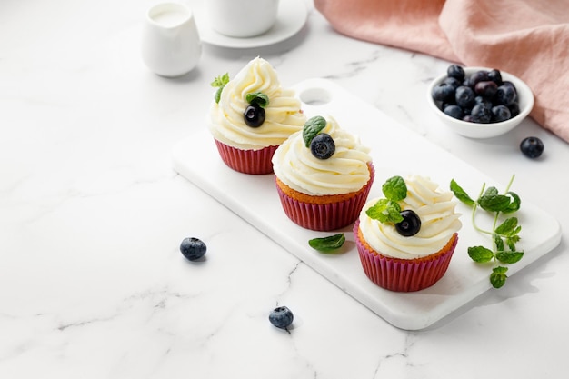 Foto cupcakes de muffins decorados com mirtilos creme e folhas de hortelã verde deliciosa sobremesa caseira