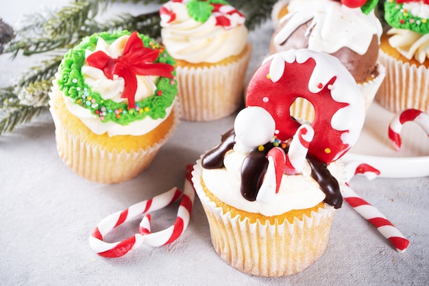 Cupcakes de natal engraçados. cupcakes doces caseiros com cobertura de açúcar em forma de decoração de natal e símbolos, em fundo de madeira com decoração de natal