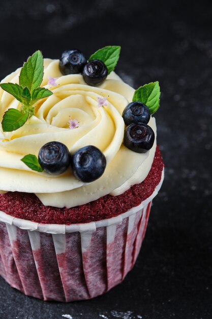 Cupcakes de veludo vermelho com creme de cream cheese. Sobremesa decorada com mirtilos frescos e hortelã.