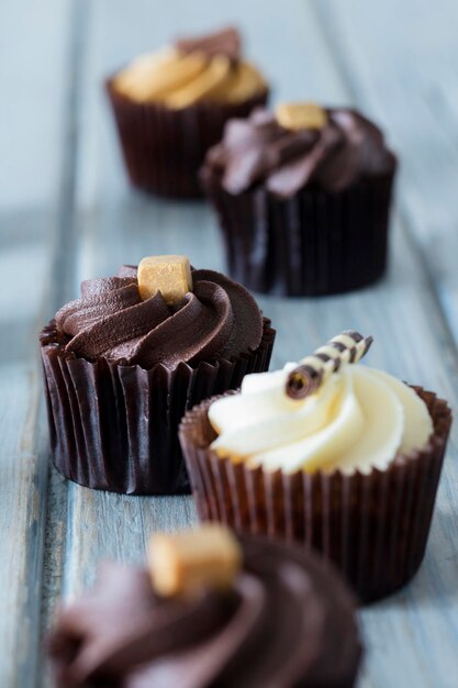 Cupcakes decorados com chocolate caramelo e cobertura de baunilha em um fundo de madeira