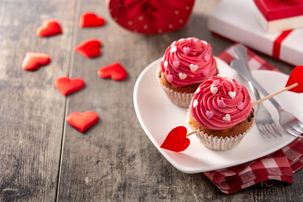Cupcakes decorados con corazones de azúcar para el día de San Valentín en mesa de madera
