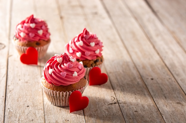 Cupcakes decorados con corazones de azúcar para el día de San Valentín en mesa de madera