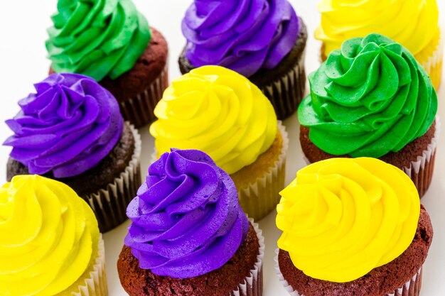 Cupcakes decorados con glaseado de colores brillantes para la fiesta de Mardi Gras.