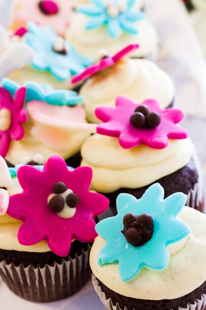 Cupcakes em miniatura decorados com flores brilhantes para a festa de casamento.