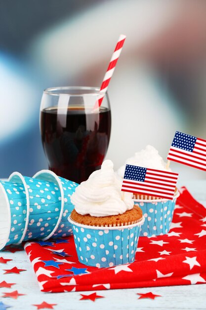 Cupcakes de fiesta patriótica americana y vaso de cola en la mesa de madera