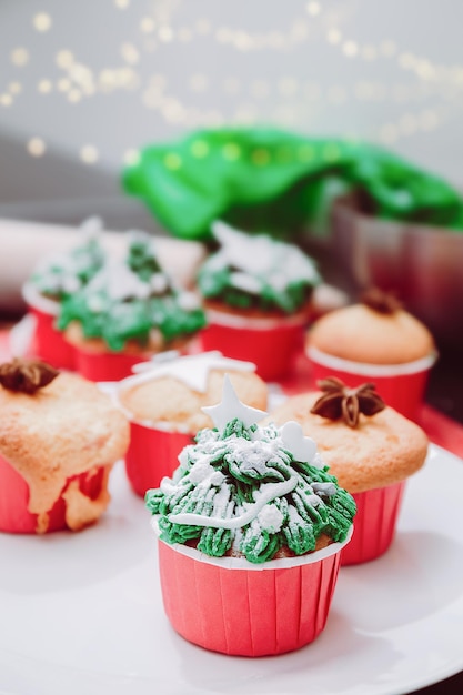 Cupcakes en forma de árbol de Navidad con chispas de nieve en las luces de Navidad y fondo festivo Tratamiento navideño de cocina para la familia