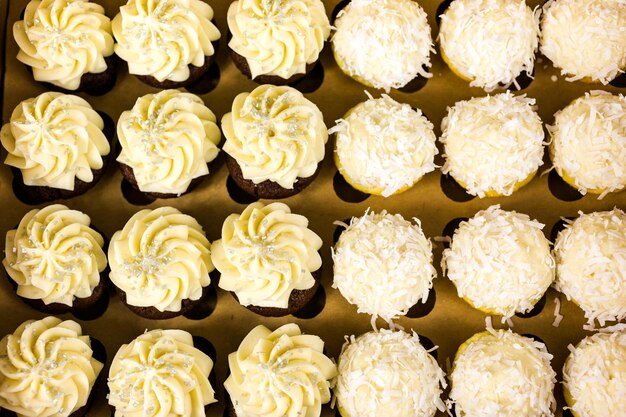 Cupcakes frescos con glaseado blanco en la caja.