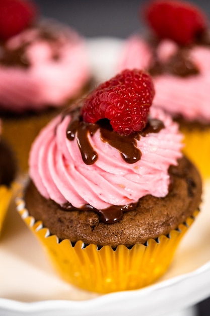 Cupcakes gourmet de chocolate y frambuesa rociados con ganache de chocolate y cubiertos con una frambuesa fresca