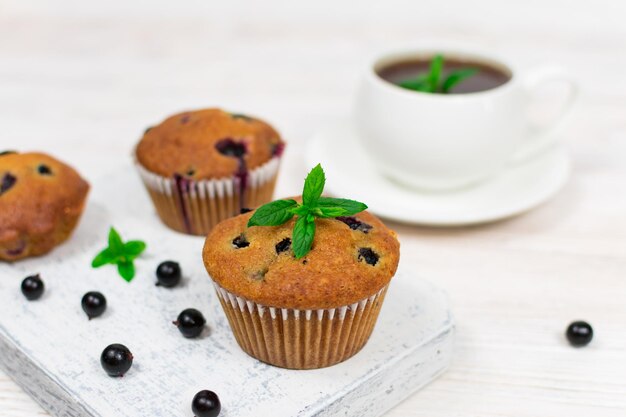 Cupcakes con grosella negra y hojas de menta en un plato blanco Enfoque selectivo