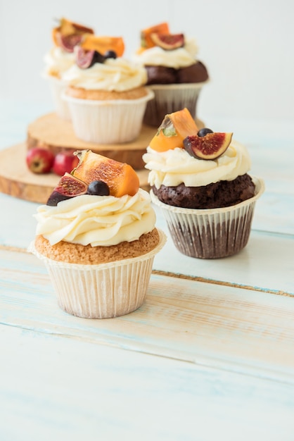 Cupcakes con higo, caqui y queso crema sobre una mesa de madera