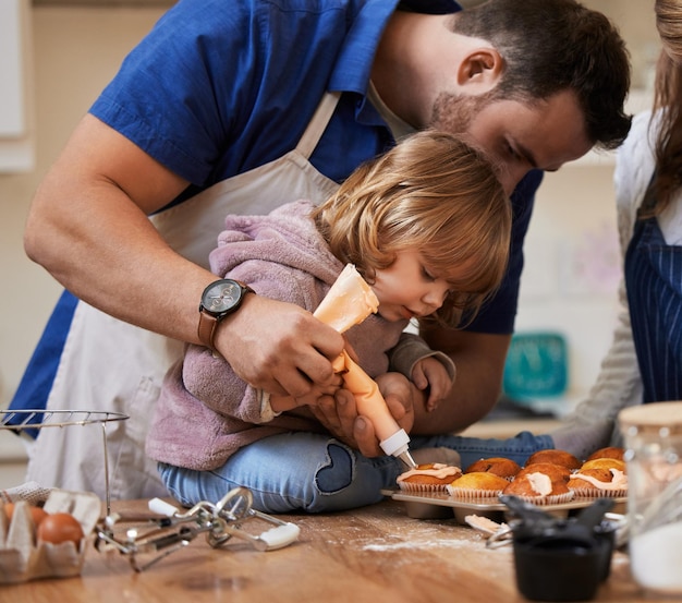 Cupcakes horneando y papá con la niña en la cocina con glaseado para vincular el aprendizaje y la diversión juntos hogar familiar y padre y hijo felices ayudando con la decoración para el postre de pastel y golosinas dulces