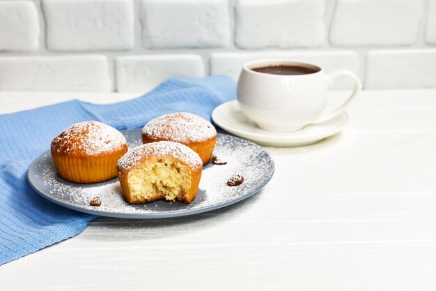 Cupcakes mit einer Tasse Tee Cupcakes mit einer weißen Tasse Tee auf einem weißen Holztisch