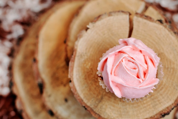 Cupcakes mit rosa Creme auf hölzernem Hintergrund.