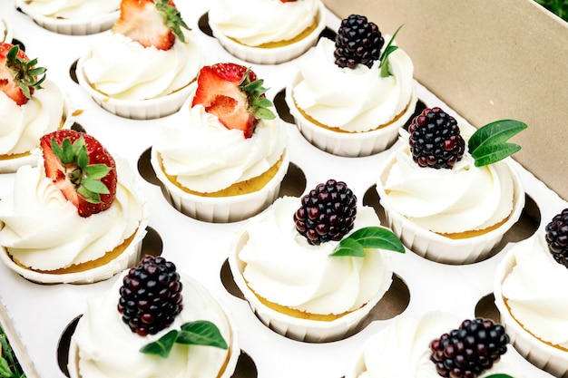 Cupcakes mit Schlagsahne und Erdbeeren und Brombeeren im Karton.