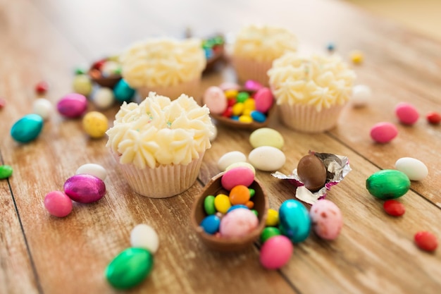 Cupcakes mit Schokolade-Eiern und Süßigkeiten auf dem Tisch