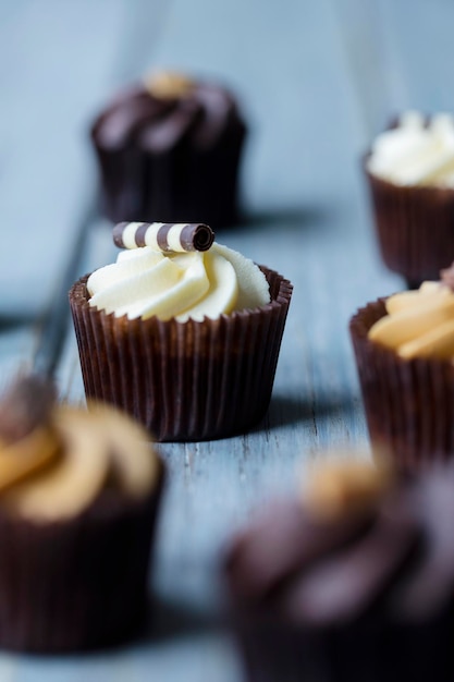 Cupcakes mit Schokoladenkaramell und Vanilleglasur auf Holzhintergrund