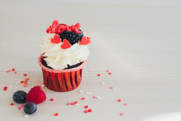 Cupcakes mit weißer Sahne, frischen Beeren und Dekoration