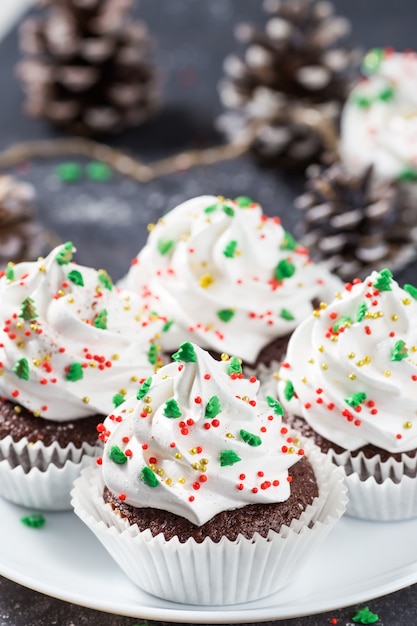 Cupcakes navideños de chocolate decorados con crema blanca y abetos Postre de año nuevo