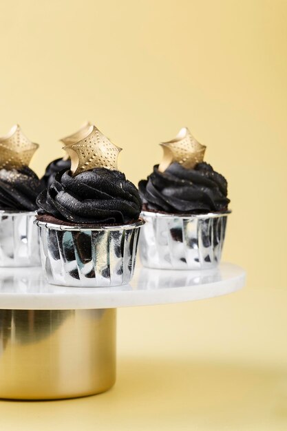 Cupcakes pretos decorados com uma estrela dourada em um carrinho de bolo