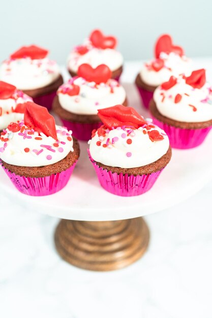 Cupcakes red velvet com cobertura de cream cheese e decorado com chocolates vermelhos em formato de coração e beijo