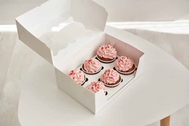 Cupcakes rosa en una caja de regalo blanca sobre una mesa blanca