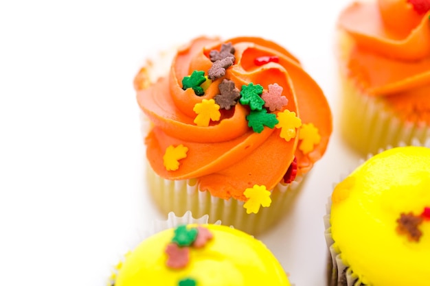 Cupcakes surtidos con glaseado amarillo y naranja decorados para el otoño.