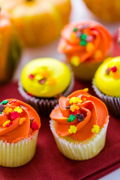 Cupcakes surtidos con glaseado amarillo y naranja decorados para el otoño.